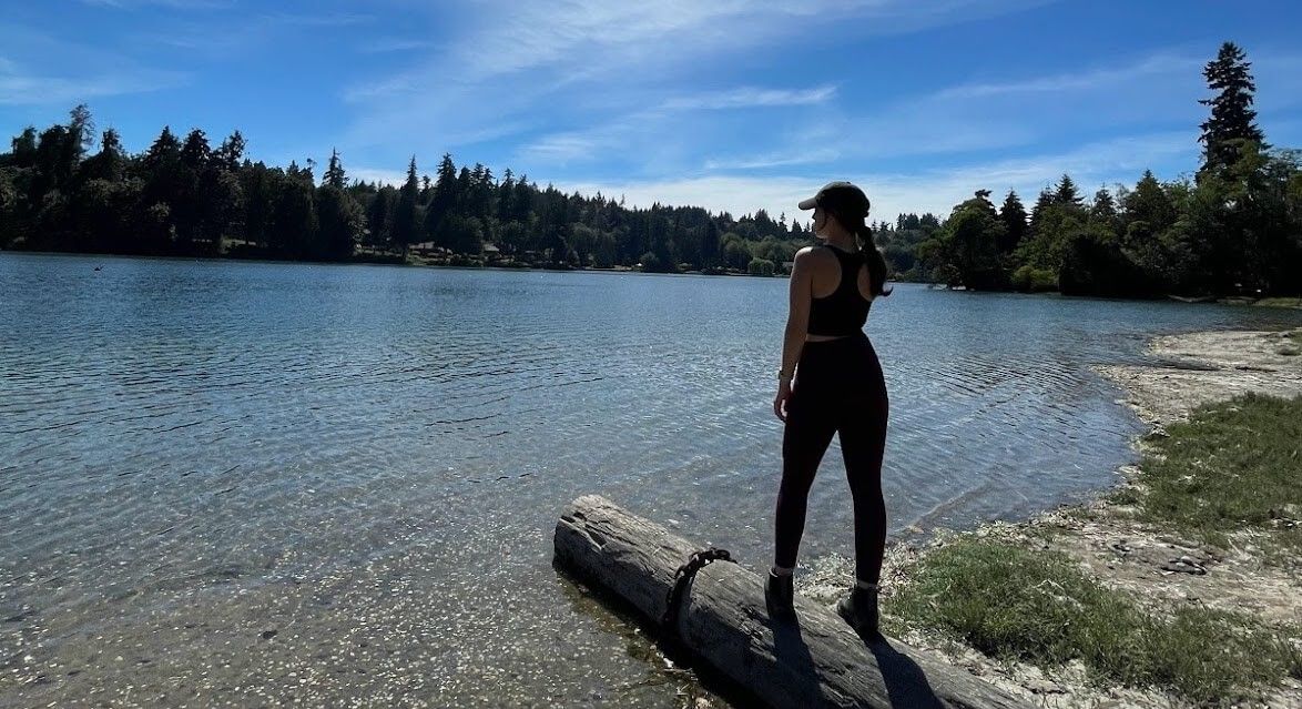Faith in athletic attire overlooking a clear lake with blue skies overhead